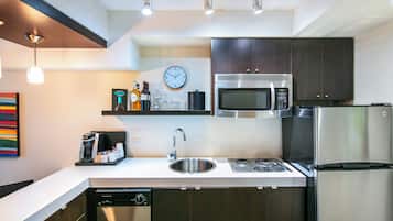 A modern kitchen with stainless steel appliances, a dishwasher, and a clock on the wall.