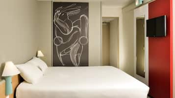 A hotel room with a bed, two bedside lamps, a wall-mounted TV, and a large abstract artwork.