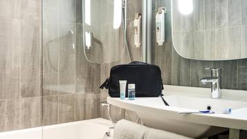 A bathroom with a bathtub, a sink, a mirror, and toiletries.