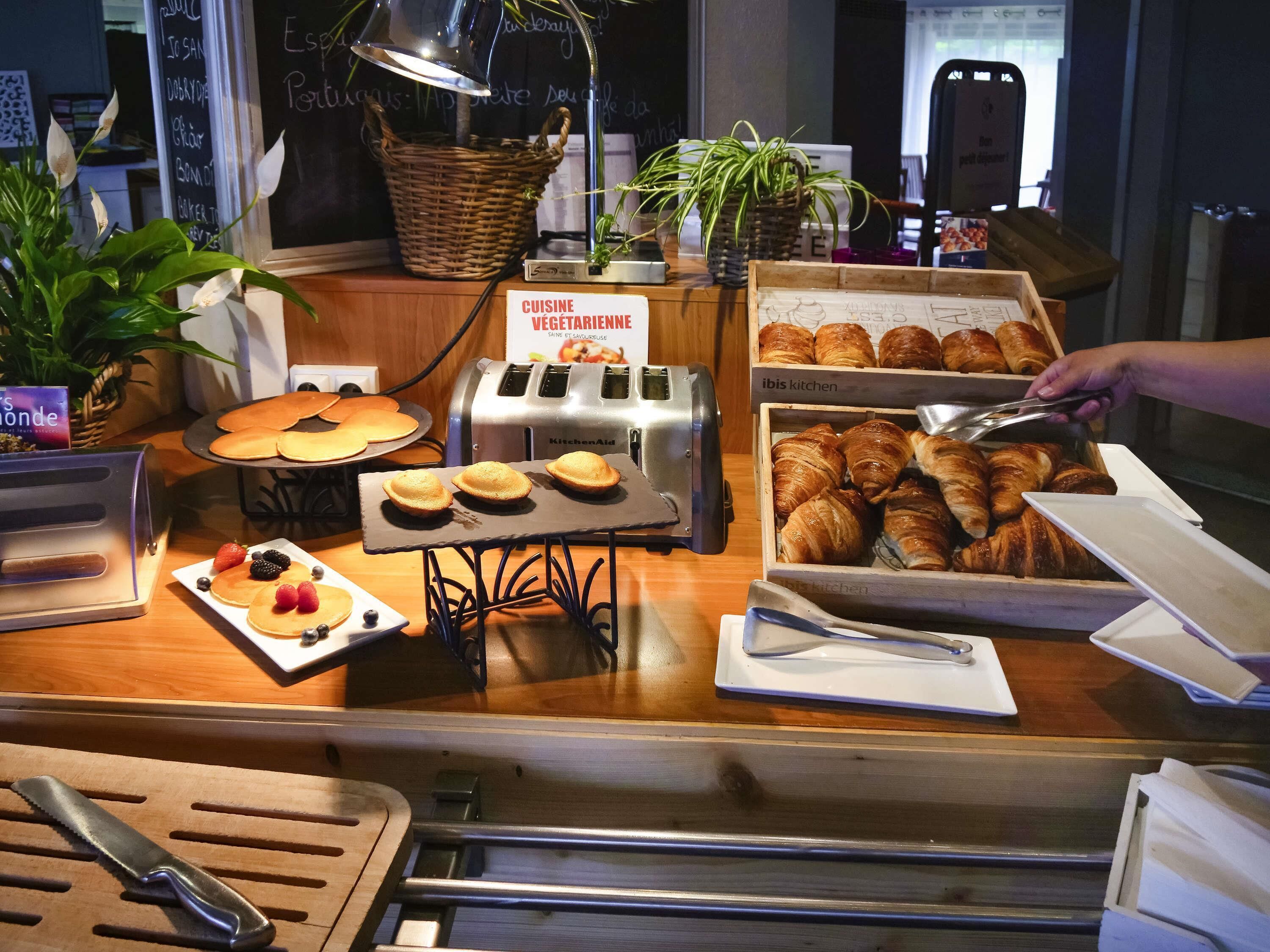 Un bufé de desayuno con pastelería, un tostador y un letrero que indica una opción vegetariana.