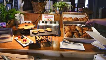Un bufé de desayuno con pastelería, un tostador y un letrero que indica una opción vegetariana.