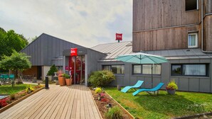 Un edificio moderno con una terraza de madera, una entrada roja y un paraguas azul.