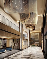 A spacious lobby with a high ceiling, a central staircase, and a modern design.