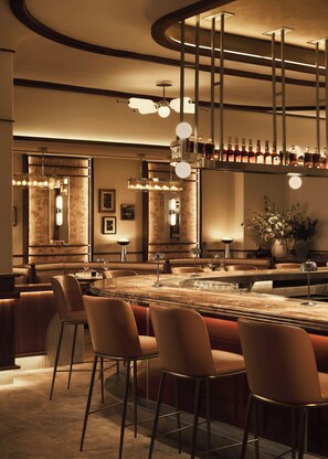 A bar area with a marble countertop, bar stools, and pendant lighting. - Loews Nashville Hotel at Vanderbilt Plaza (Nashville)