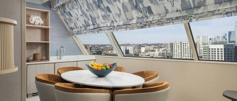 Un comedor con una mesa redonda, cuatro sillas y un cuenco de fruta.