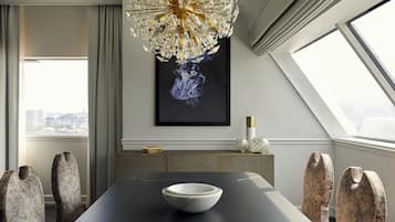 Un comedor moderno con una mesa oscura, un cuenco blanco y sillas originales. Un candelabro cuelga del techo, y una obra enmarcada adorna la pared.
