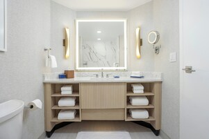 Un baño moderno con lavamanos de mármol, toalleros y un espejo grande.