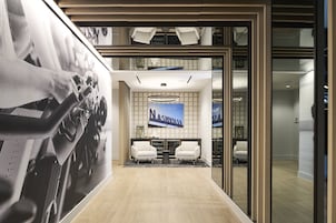 A modern lobby with a large poster, two white chairs, and a 'Nashville' sign.