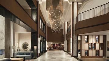 A spacious lobby with a high ceiling, a central chandelier, and a seating area with a sofa and armchairs.