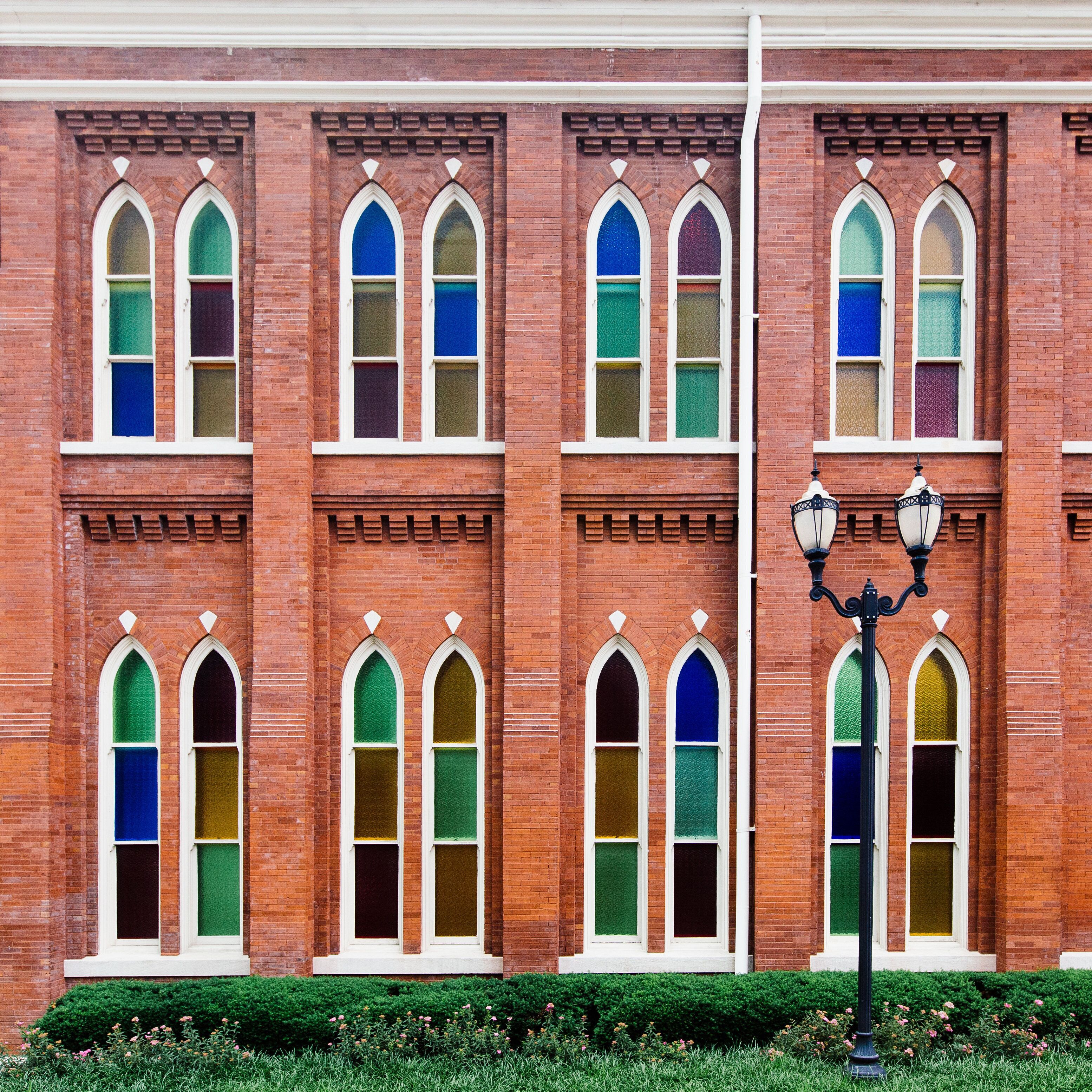 A red brick building with multiple arched windows and a street lamp in front.