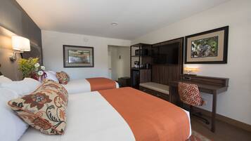 A hotel room with two beds, a desk, a chair, a TV, and a microwave.
