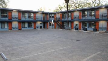 A modern multi-story building with a central courtyard, featuring a staircase, multiple windows, and outdoor planters.