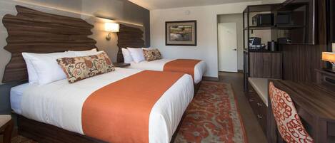 A hotel room with two beds, a desk with a chair, a television, and a microwave.