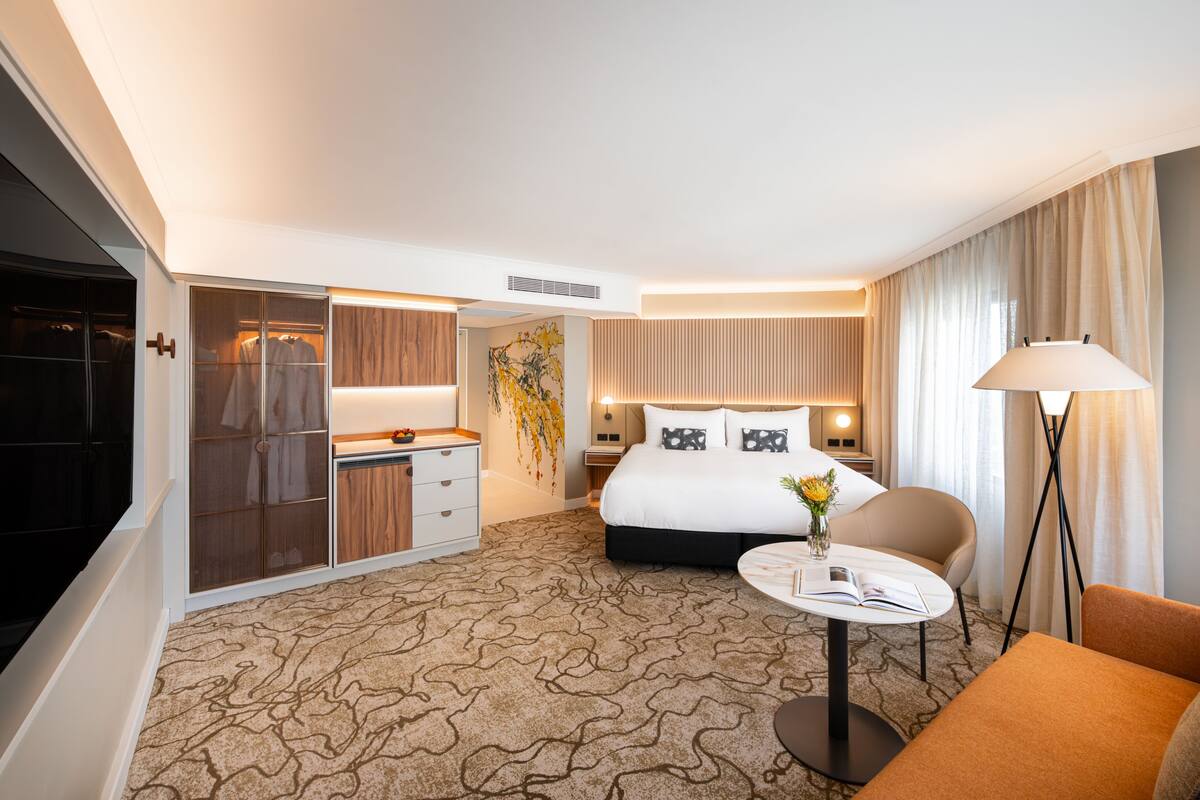 Ein Hotelzimmer mit einem Bett, Nachttisch, Stuhl und einem Schrank mit Schiebetüren.