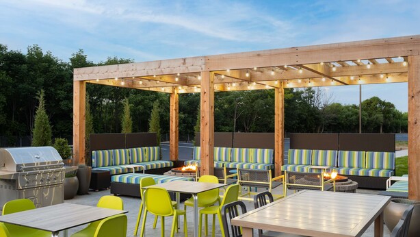 Un patio al aire libre con asientos, una parrilla y mesas.