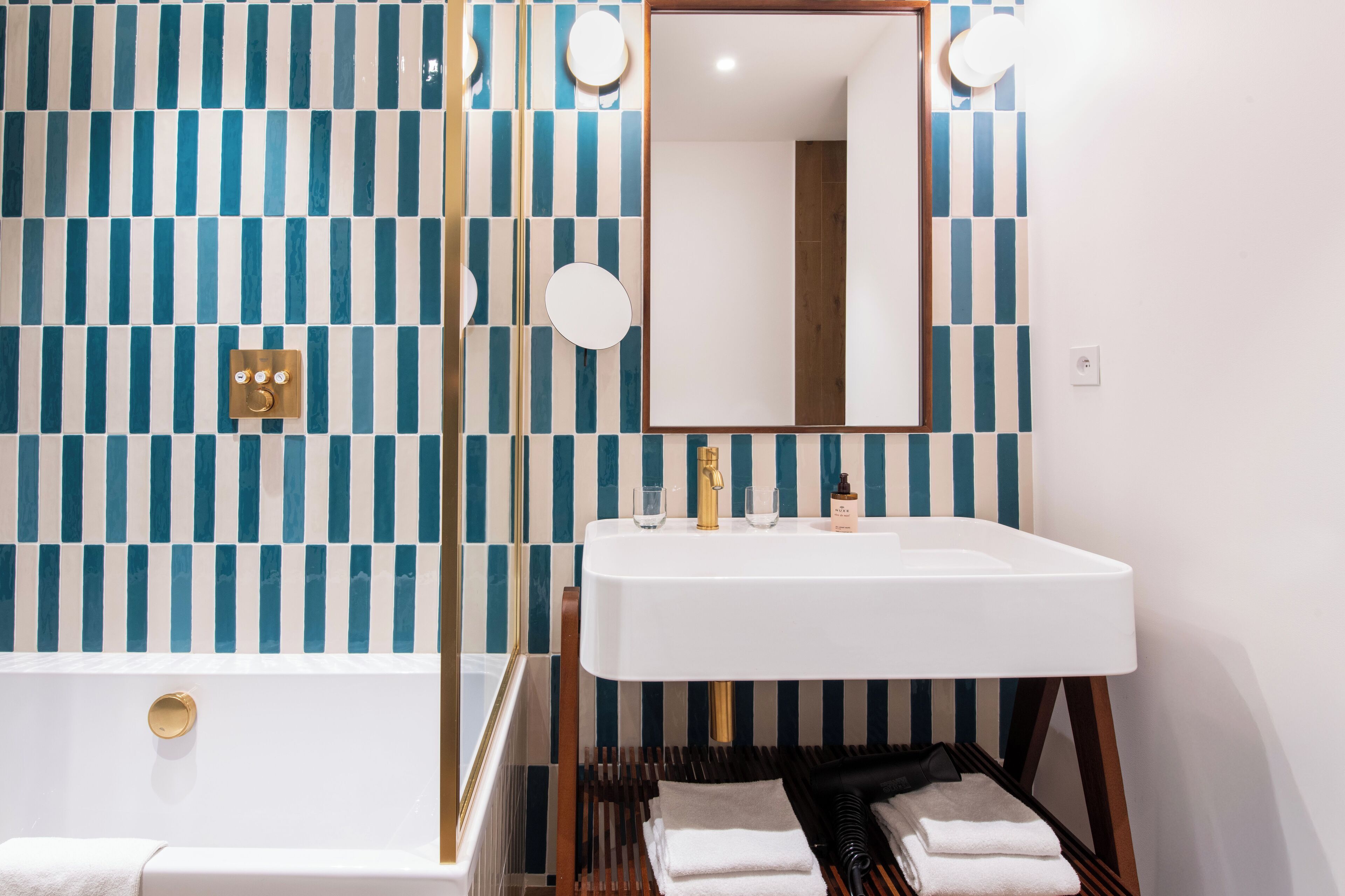 A bathroom with a white sink, a mirror, and a blue and white striped wall.