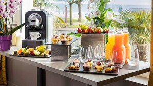 Buffet de l'esmorzar amb màquina de cafè, varietat de fruites, postres i ampolles de suc.
