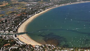 Vista aèria d'una ciutat costanera amb una platja, vaixells i zones residencials.