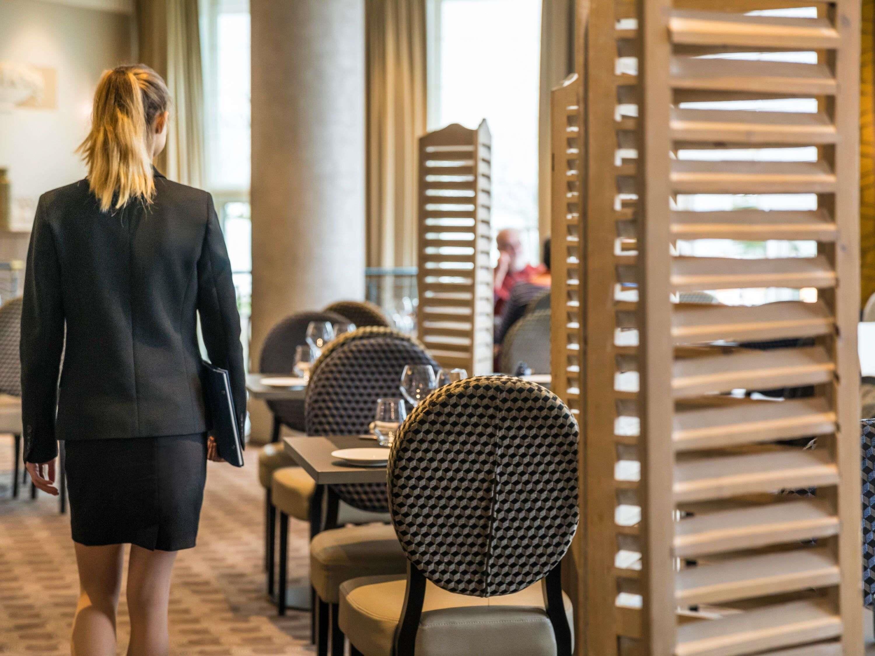 Una persona caminando por el vestíbulo de un hotel con una decoración moderna, que incluye sillas con estampado y una columna central.
