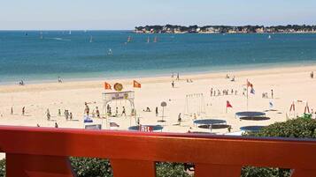 A beach with a lifeguard tower, beach umbrellas, and a clear view of the sea.