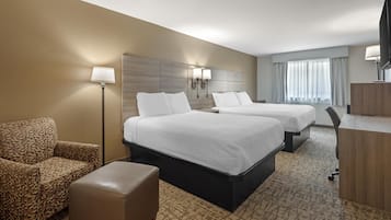 A hotel room with two beds, a sofa, a desk, and a TV.