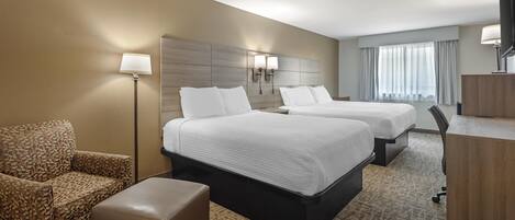A hotel room with two beds, a sofa, a desk, and a TV.