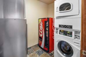 A compact laundry room with a washing machine, a dryer, and a vending machine.