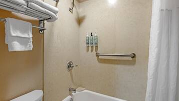 A bathroom with a bathtub, a toilet, a towel rack, and toiletries.