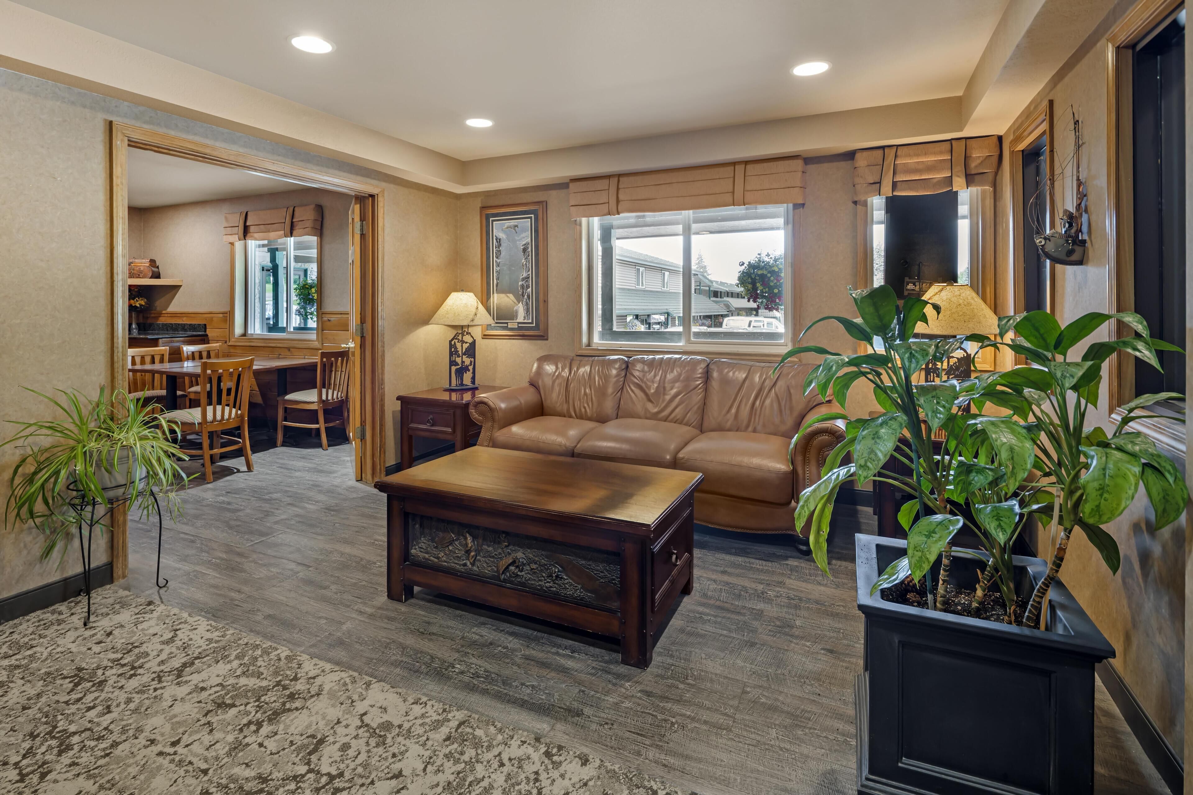 A living room with a leather sofa, a coffee table, and a dining area with a table and chairs.