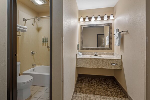 A bathroom with a bathtub, toilet, sink, and a shower area.