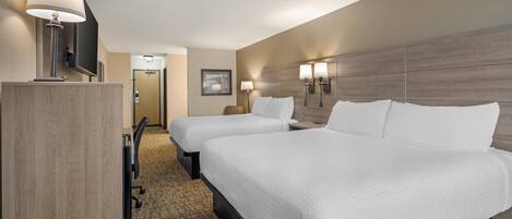 A hotel room with two beds, a desk, a chair, a TV, and a door leading to a bathroom.