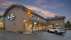 Ein Best Western Bidarka Inn mit steinverkleideter Fassade, einer überdachten Außenbereiches mit Geländer und einem Parkplatz mit markierten Stellplätzen.