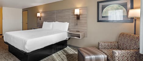 A hotel room with a bed, bedside tables, a chair, and a wall-mounted lamp.