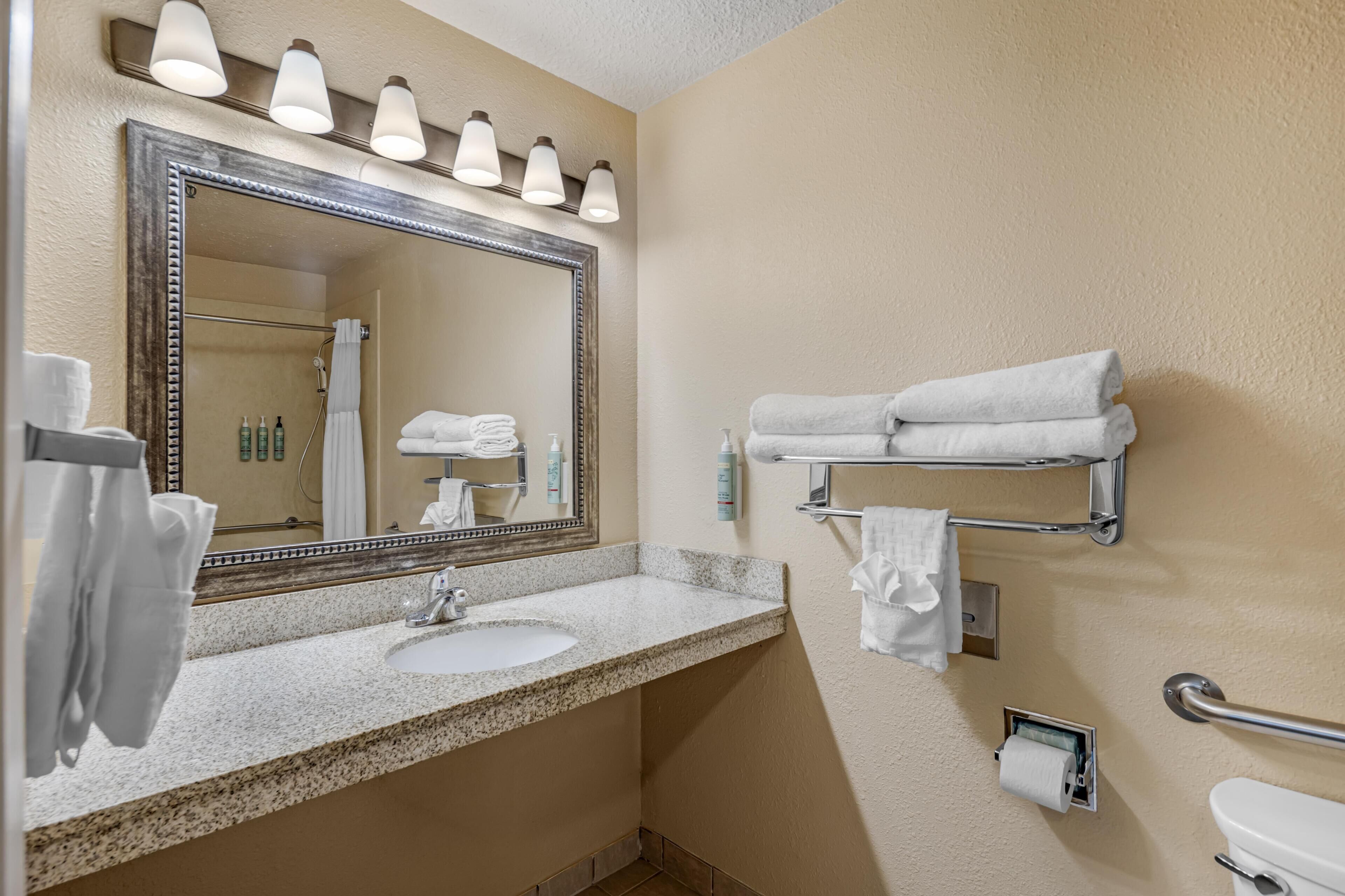 A bathroom with a sink, mirror, towel rack, and toilet.