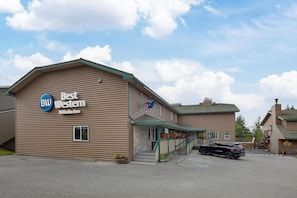 A building with a sign reading 'Best Western' and a flag. There is a parking lot in front.
