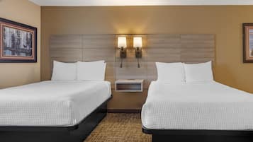 Habitación de hotel con dos camas individuales, una mesita de noche y dos lámparas de pared.