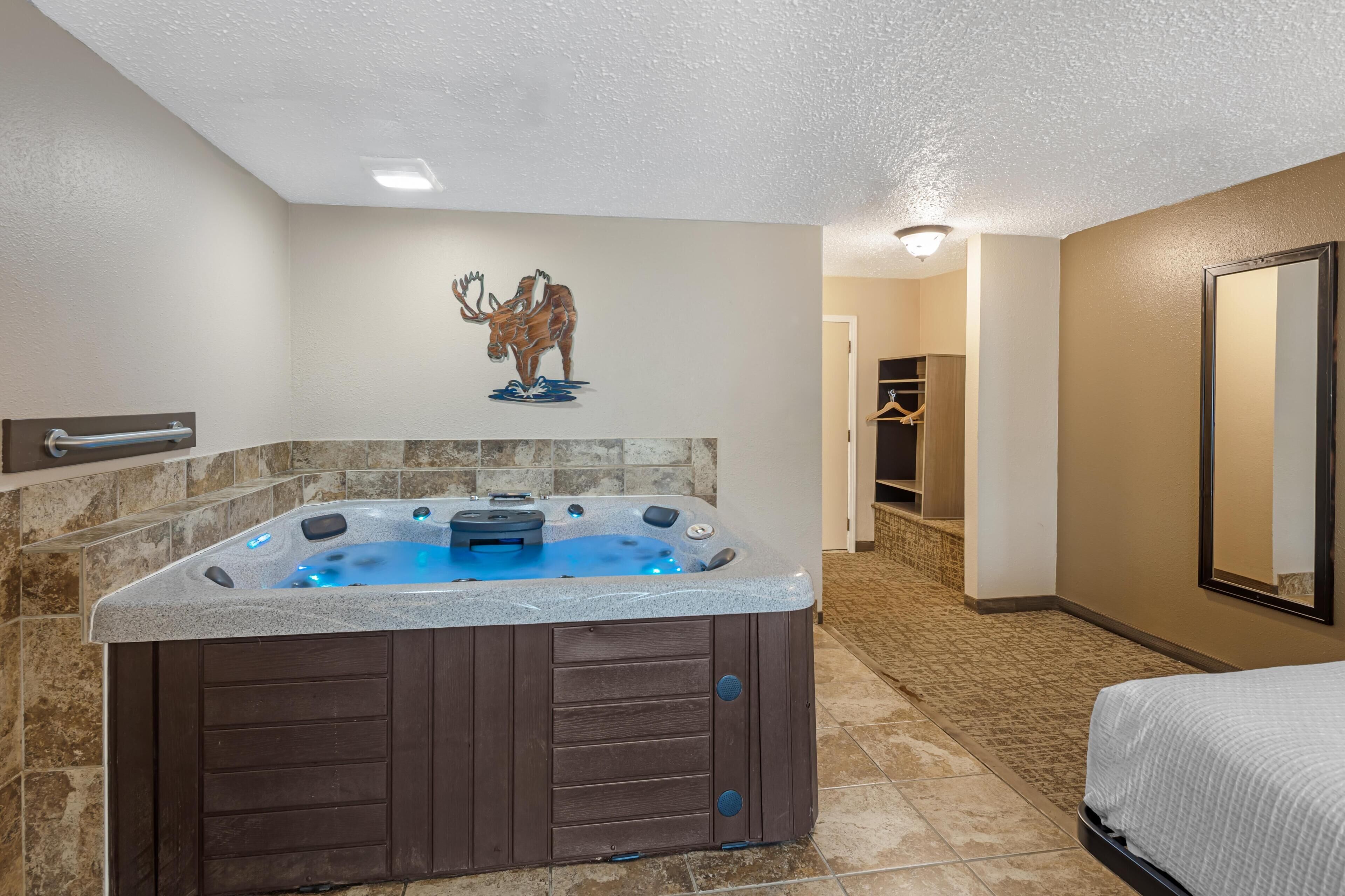 A bathroom with a hot tub, a wooden wall decoration, and a mirror.