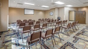 A conference room with rows of foldable chairs, a projector screen, and a patterned carpet. - Best Western Bidarka Inn (Homer)