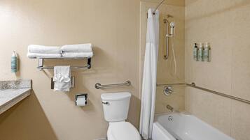 A bathroom with a toilet, a bathtub, a shower, and a towel rack with folded towels.