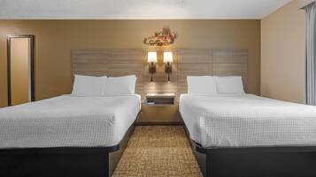 Ein Hotelzimmer mit zwei Betten, einem Kopfteil mit einer Leuchte und einem Teppichboden.
