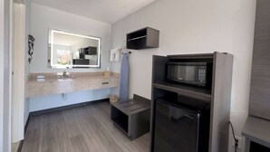 A compact kitchenette with a microwave, refrigerator, and a small cabinet.