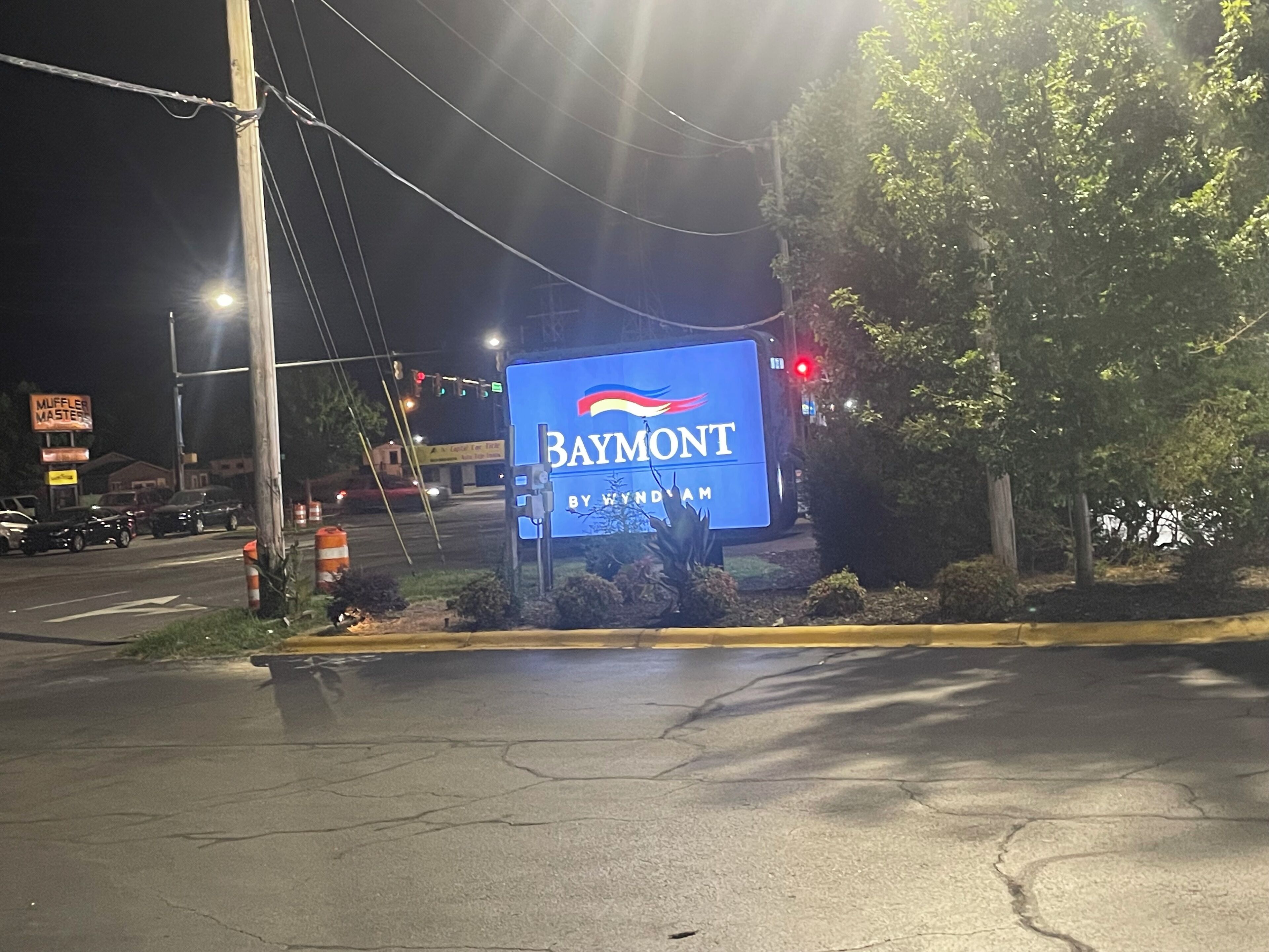 A nighttime street view with a large illuminated sign for Baymont by Wyndham.