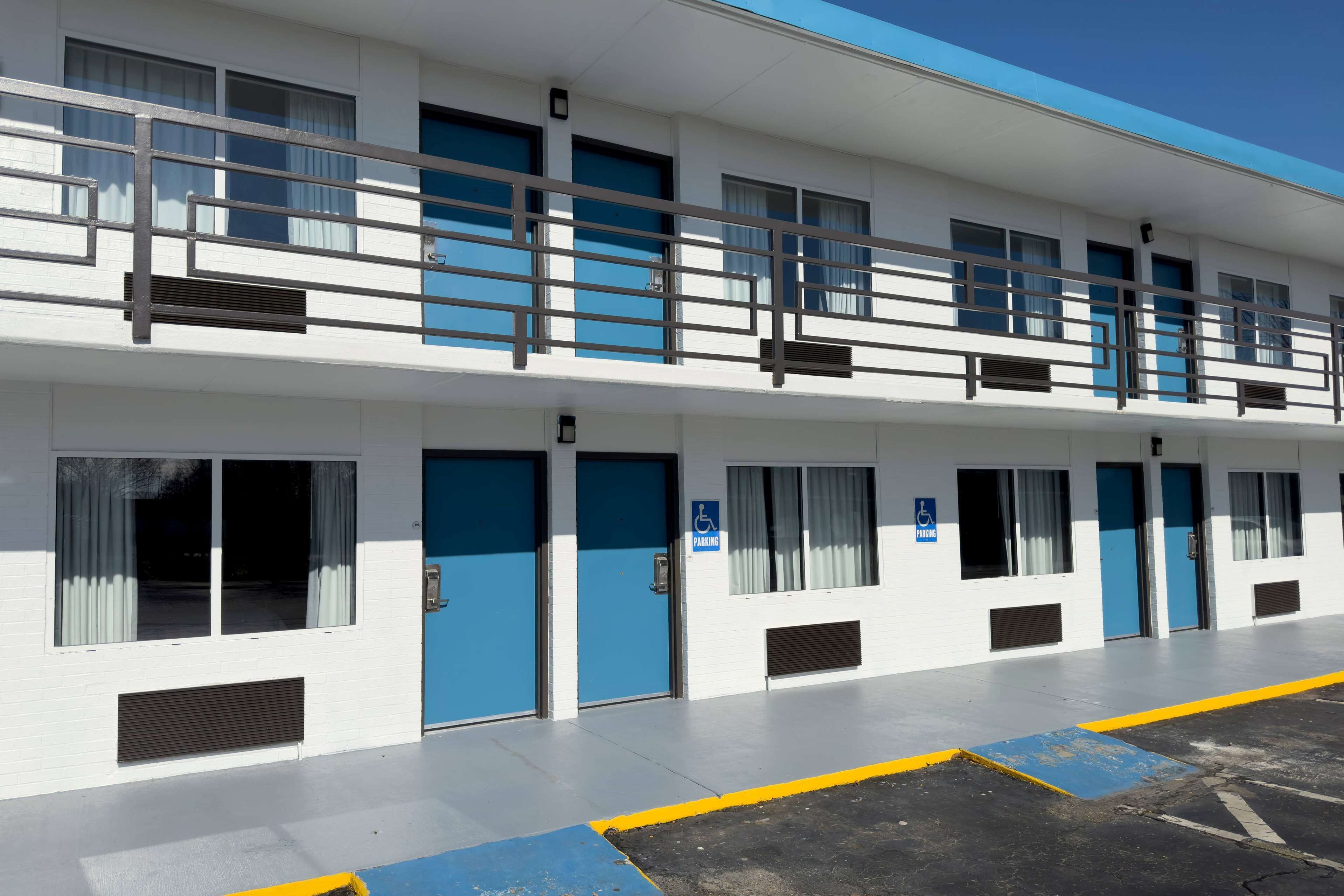 A two-story building with blue doors and windows, a ramp, and a parking area with blue and yellow markings.
