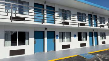 A two-story building with blue doors and windows, a ramp, and a parking area with blue and yellow markings.