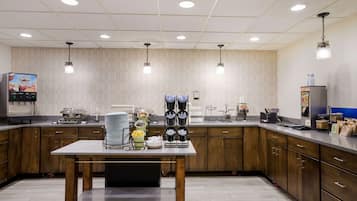 A modern kitchen with wooden cabinets, a central island, and various appliances including a coffee machine and a microwave.