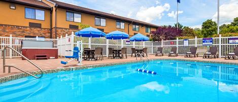 A swimming pool with lounge chairs and umbrellas, a lifeguard stand, and a flagpole with a flag.