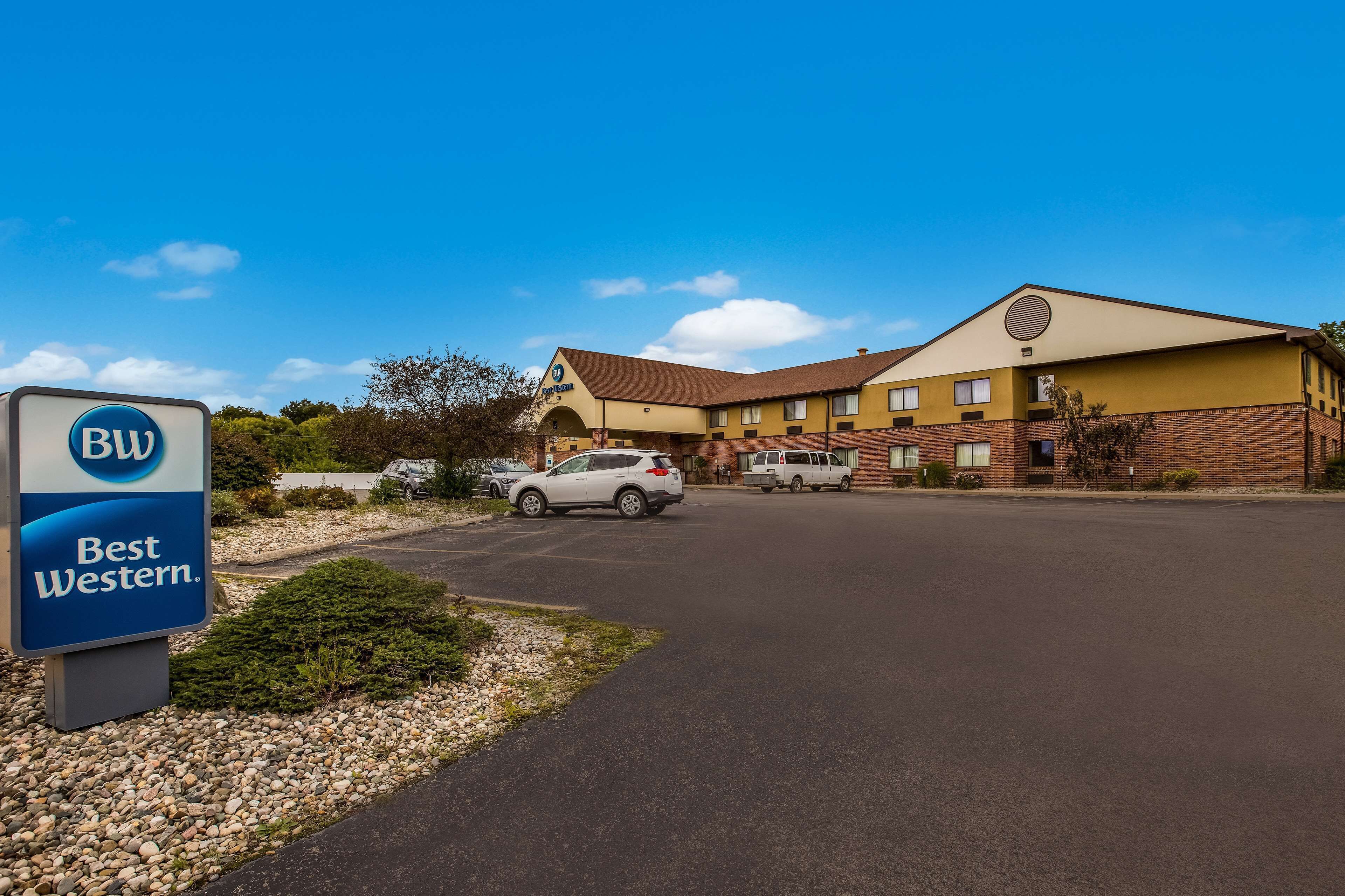 A Best Western hotel with a parking lot, a sign, and a building with a brown roof and yellow walls.