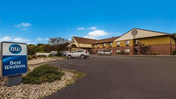 A Best Western hotel with a parking lot, a sign, and a building with a brown roof and yellow walls.