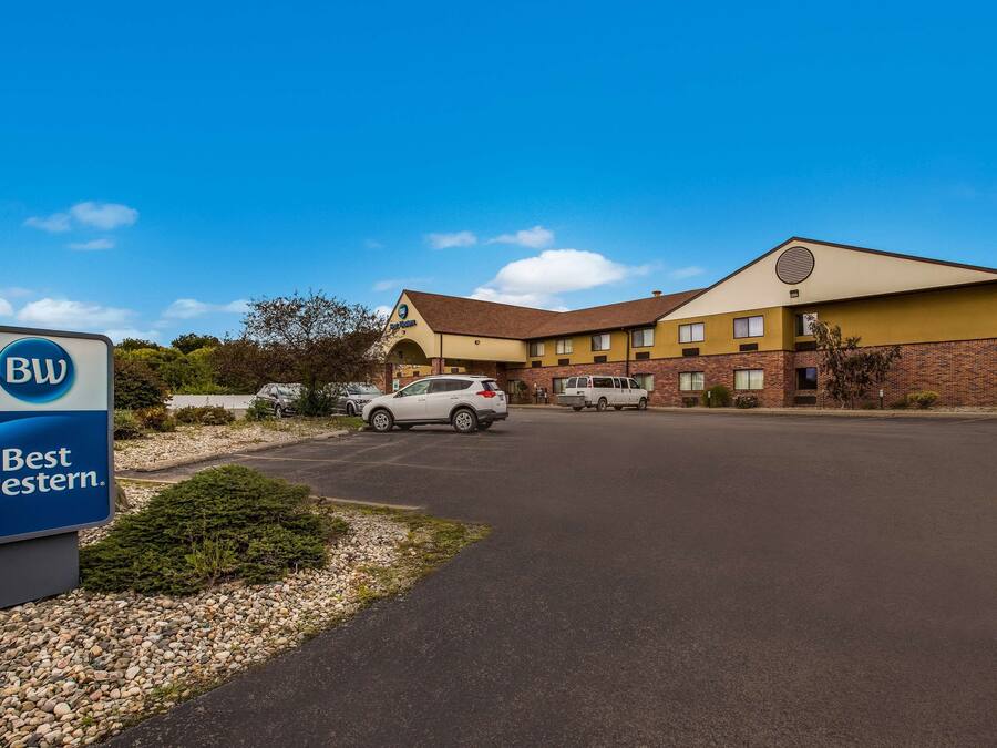 A Best Western hotel with a parking lot, a sign, and a building with a brown roof and yellow walls.