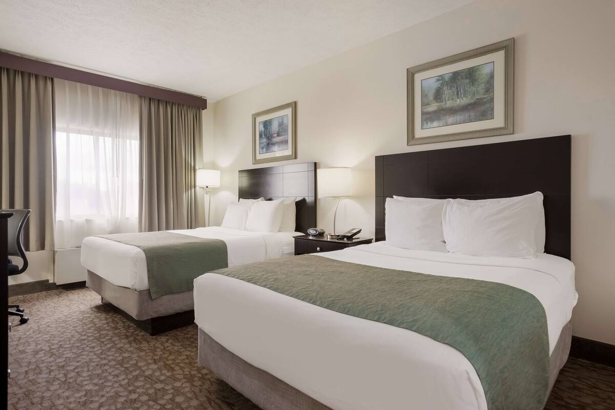 Ein Hotelzimmer mit zwei Betten, einem Schreibtisch und einem Stuhl.